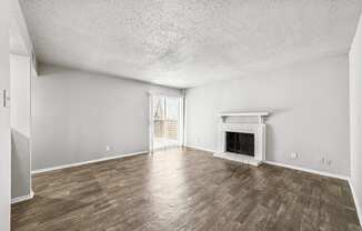 A room with a fireplace and wood flooring.