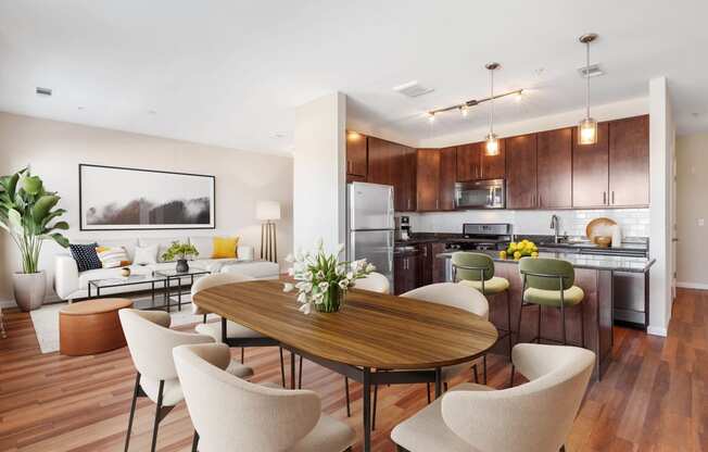 a living and dining room area with a kitchen in the background and a large table in the at West 130, West Hempstead New York