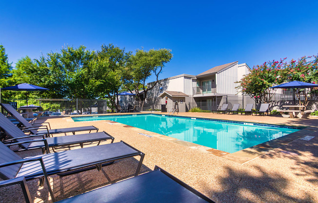 A pool surrounded by chairs and trees at The Biltmore Apartments located in the Vickery Midtown neighborhood of Dallas, TX.