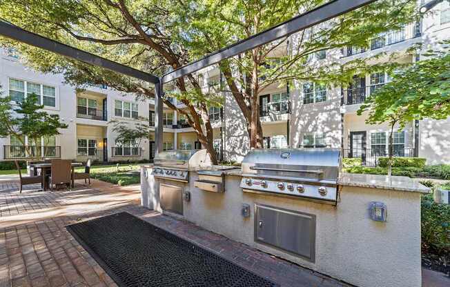 an outdoor kitchen with stainless steel appliances in front of an apartment building