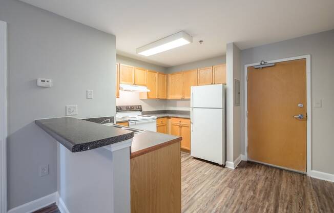 an empty kitchen with white appliances and wooden cabinets at Crogman School Lofts, Georgia