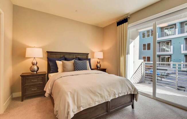 A bedroom with a large bed and a view of a balcony.