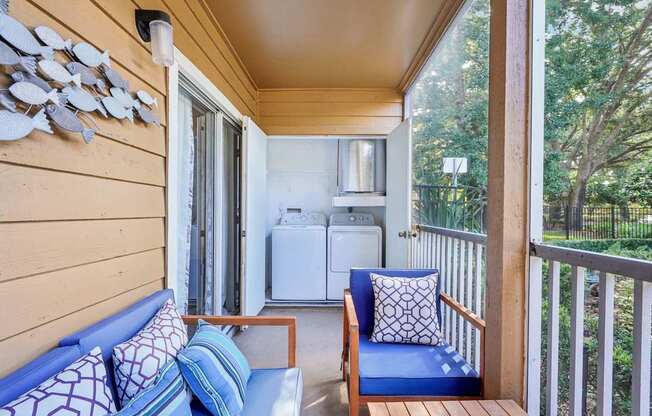 A blue couch with a white pillow is on a wooden balcony.