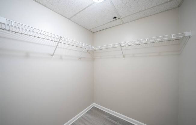 Empty white walk in closet with shelves.