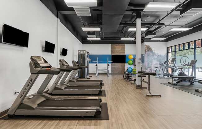 a gym with treadmills and other exercise equipment on a wooden floor