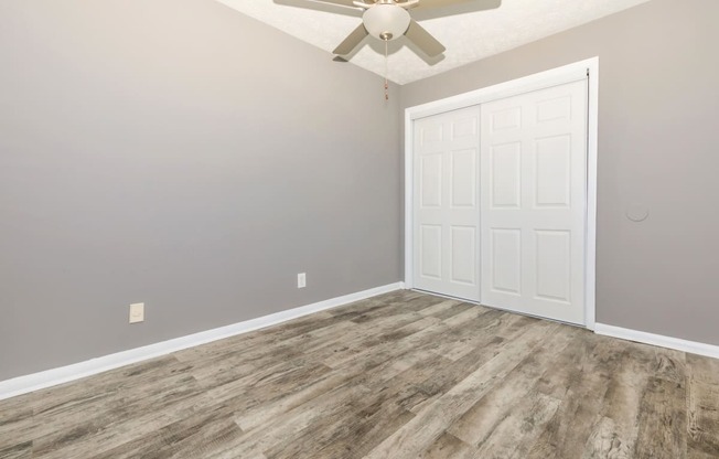 an empty room with a ceiling fan and a white door