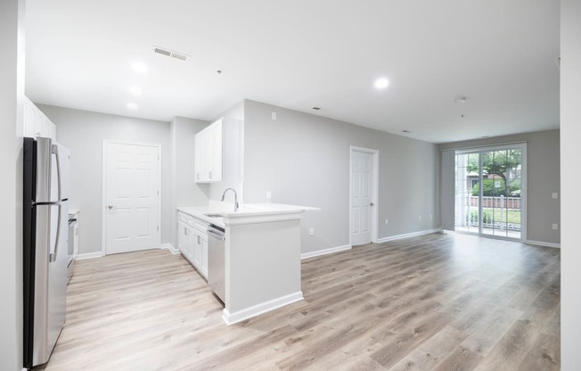 an empty kitchen and living room with a refrigerator and a sink