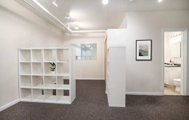 a room with a white shelving unit and a bathroom