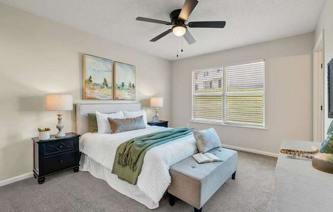 A bedroom with a bed, nightstand, and window with blinds.