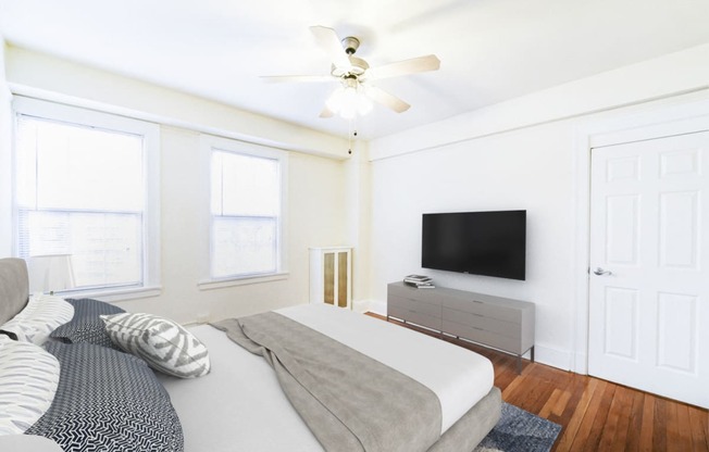 bedroom with bed, dresser, tv, hardwood floors, large windows , and ceiling fan at wakefield hall apartments in washington dc