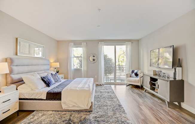 a bedroom with a bed and a tv and a door to a balcony