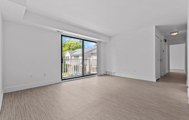 an empty living room with a sliding glass door leading to a balcony