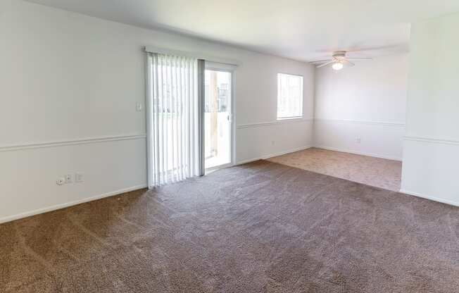 an empty living room with white walls and a sliding glass door