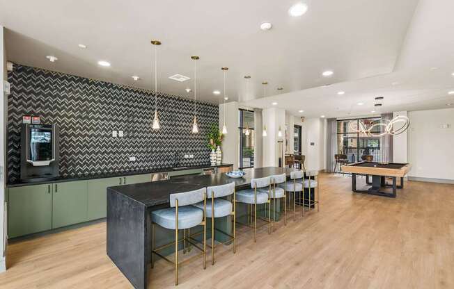 A modern kitchen with a black island and green cabinets.