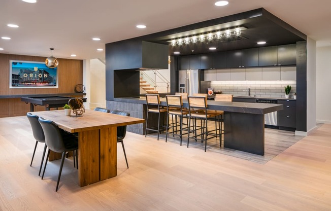 the kitchen and dining area of a modern home with a wood floor and black cabinets