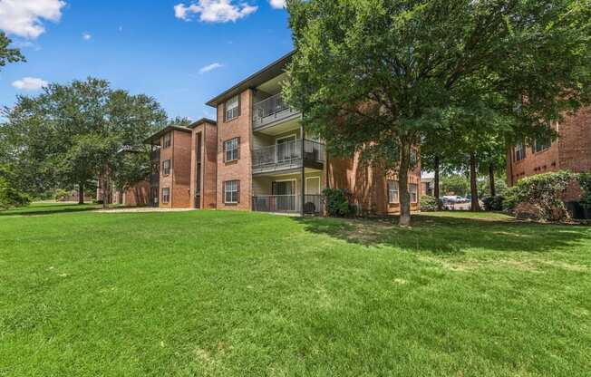 A grassy area in front of a brick apartment building.