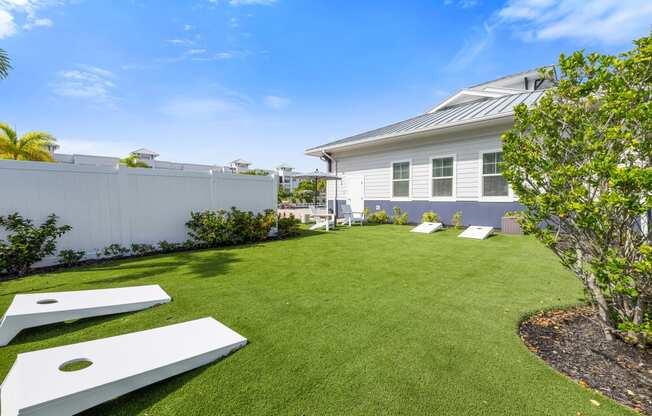 lawn area with corn hole game and a white fence