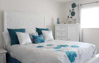 a bedroom with a white bed with blue and white pillows and a white head