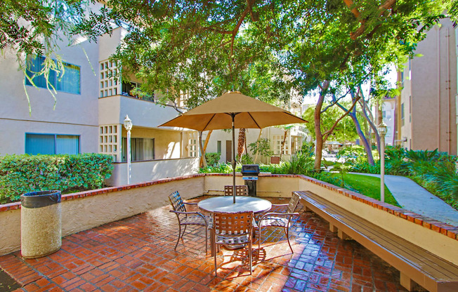 Resort-like picnic and barbecue area with wood bench, lush landscaping