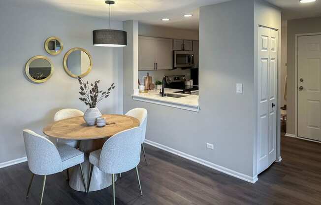 a dining area with a table and chairs and a kitchen in the background