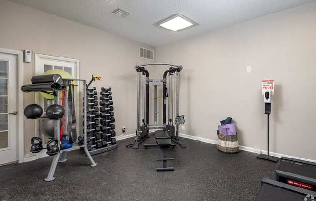 A gym room with a variety of equipment including weights and cardio machines.