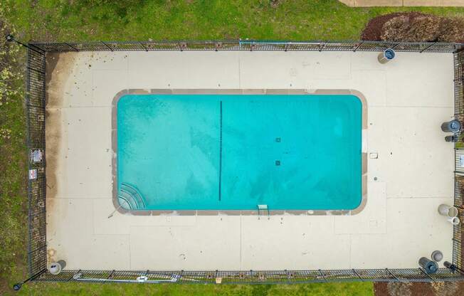 an aerial view of a swimming pool with green grass around it