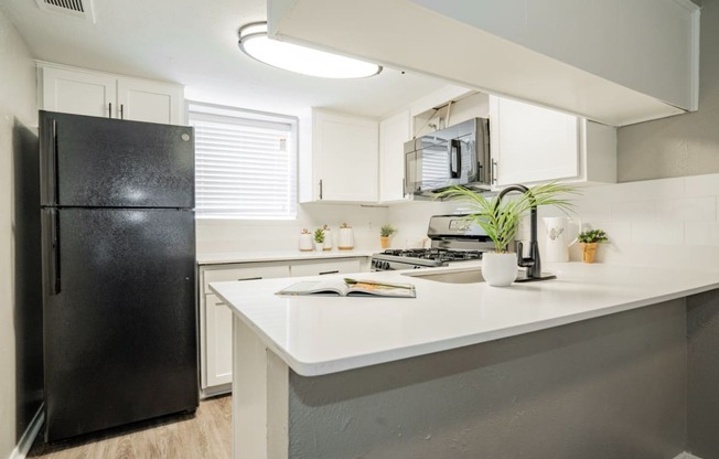 a kitchen with a white counter top and a black refrigerator