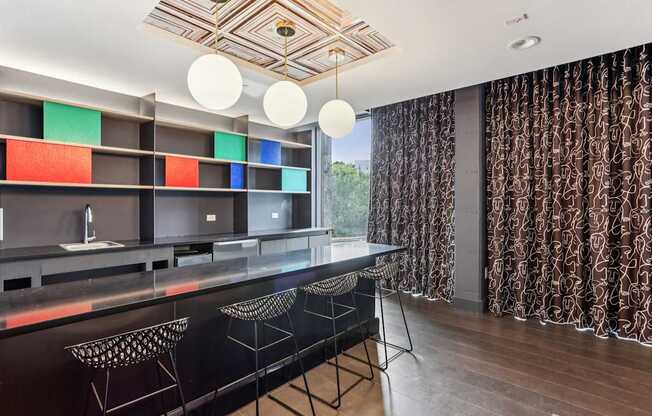 A modern kitchen with a black countertop and bar stools.