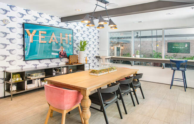 a dining area with a wooden table and chairs and a large flat screen tv on the wall