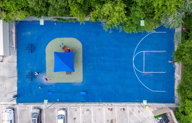 A blue rectangular pool with a basketball court in the middle.