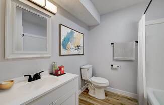 A white toilet sits in a bathroom next to a sink and a shower at The Hampton Meadows Apartments, Des Moines, IA