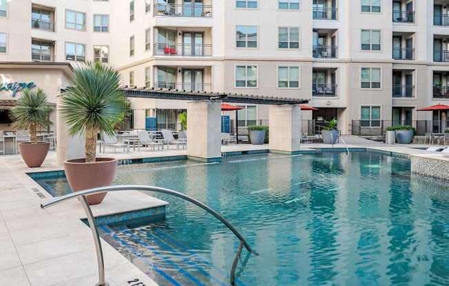 A pool in front of a building with a palm tree.