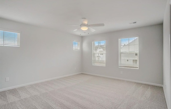 A room with a carpeted floor and a ceiling fan.