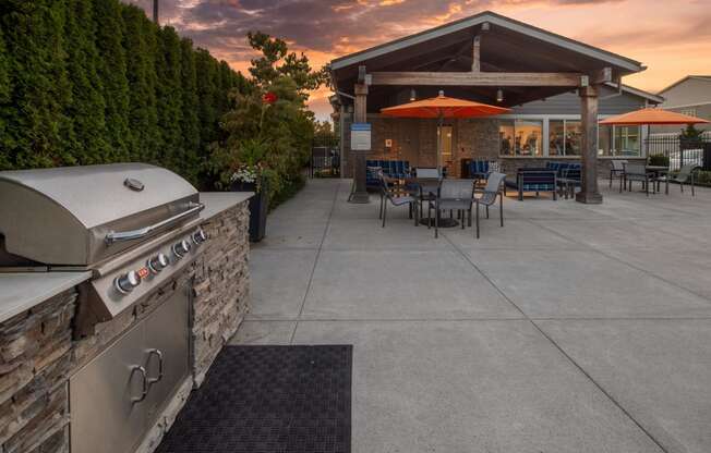 a patio with a grill and tables with umbrellas