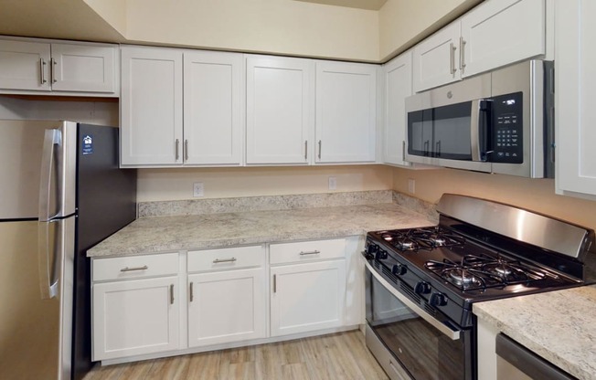 Renovated kitchen with white cabinets and a stove and a microwave