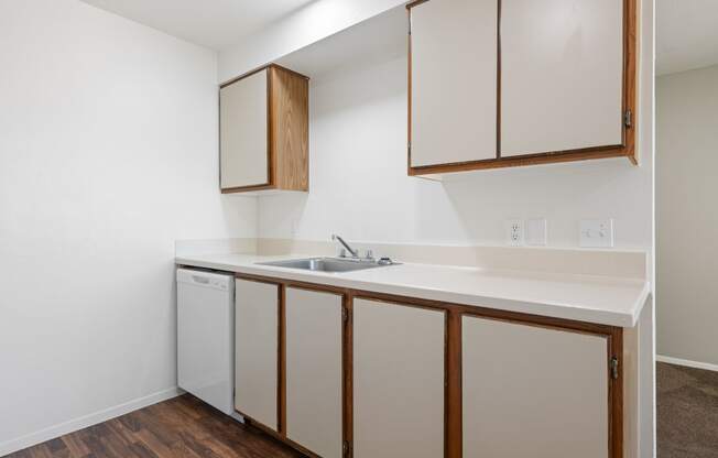 a kitchen with white appliances and wood flooring in an apartment