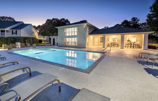 a swimming pool with chairs around it in front of a house