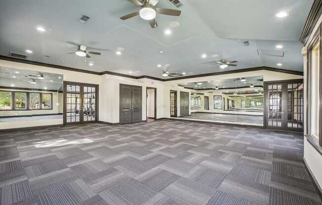 A spacious room with a carpeted floor and ceiling fans.