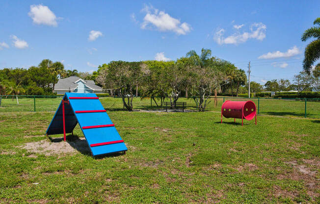 a playground with a blue slide and a red barrel