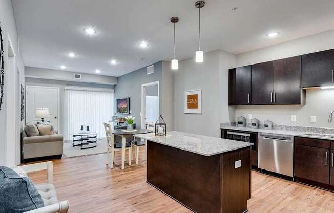 a kitchen with an island and a living room with a couch. Circle Pines, MN Lexington Lofts