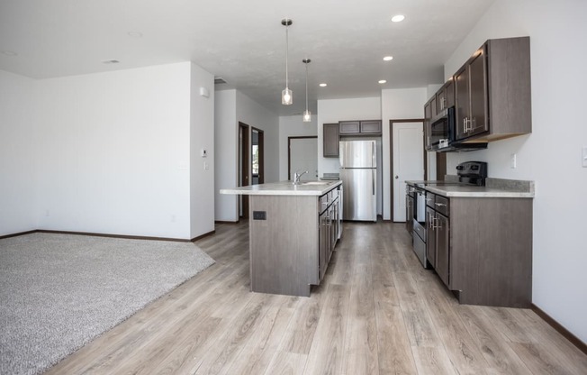 a kitchen and living room with wooden floors and stainless steel appliances