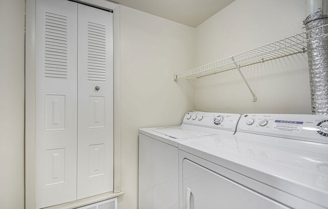 a white laundry room with a washer and dryer and a closet