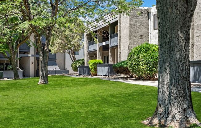 an apartment building with green grass and trees in front of it