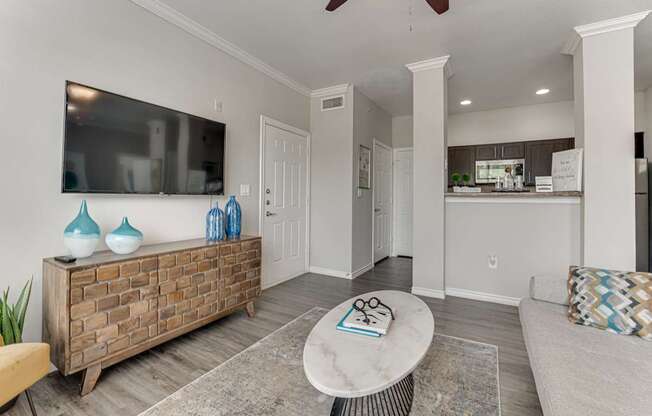 A living room with a white ceiling fan and a flat screen TV mounted on the wall.
