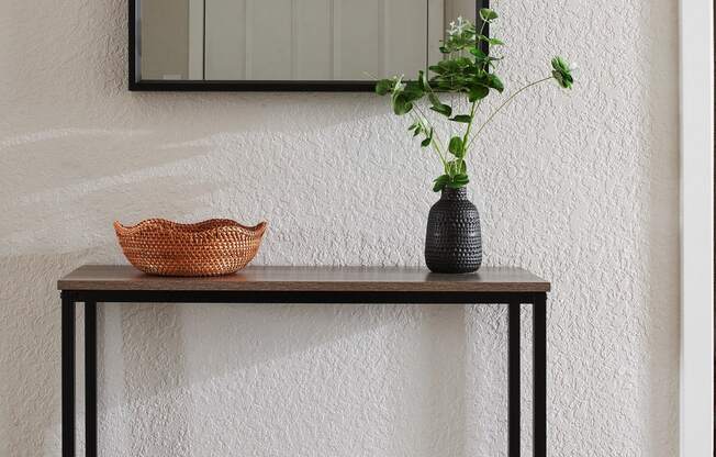 a console table with a vase and bowl on top and a mirror hanging above it