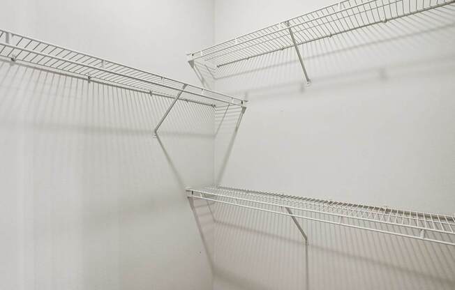 A close up of a wire shelf against a white wall.