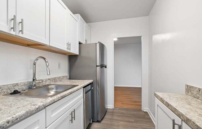 A kitchen with white cabinets and a marble countertop.