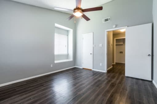 an empty living room with wood floors and a ceiling fan