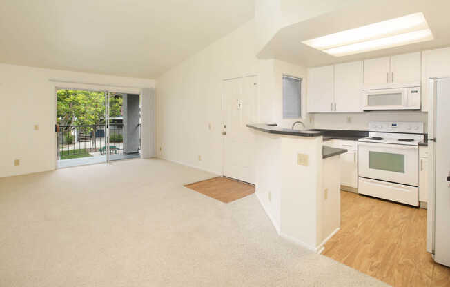 Kitchen and Carpeted Living Room with Balcony