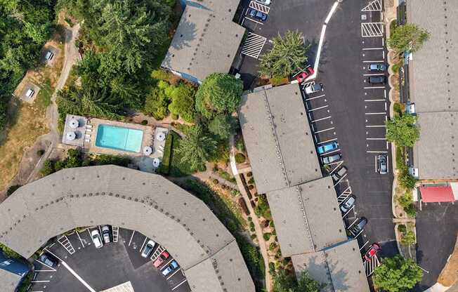 A parking lot with cars and a building with a pool.